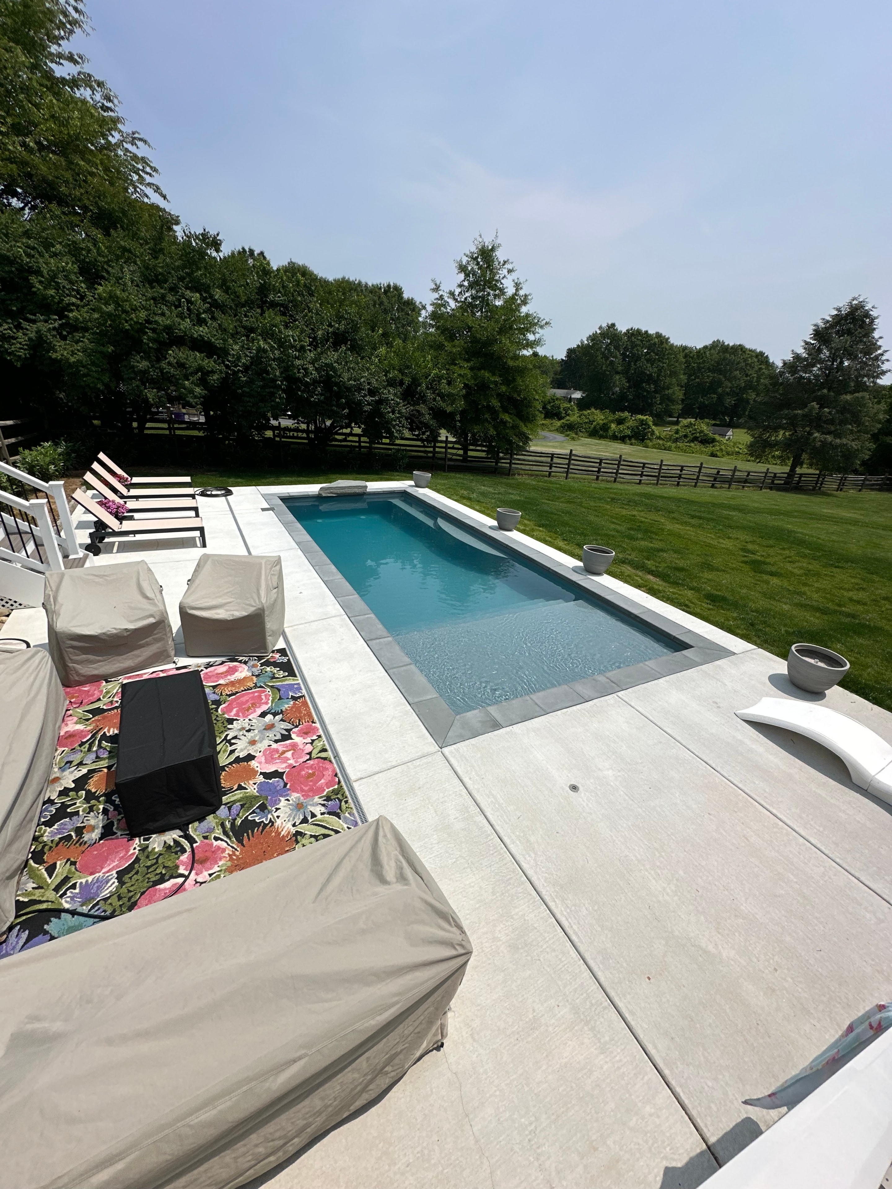 LandPro pool with concrete surround, lounge chairs, and open yard