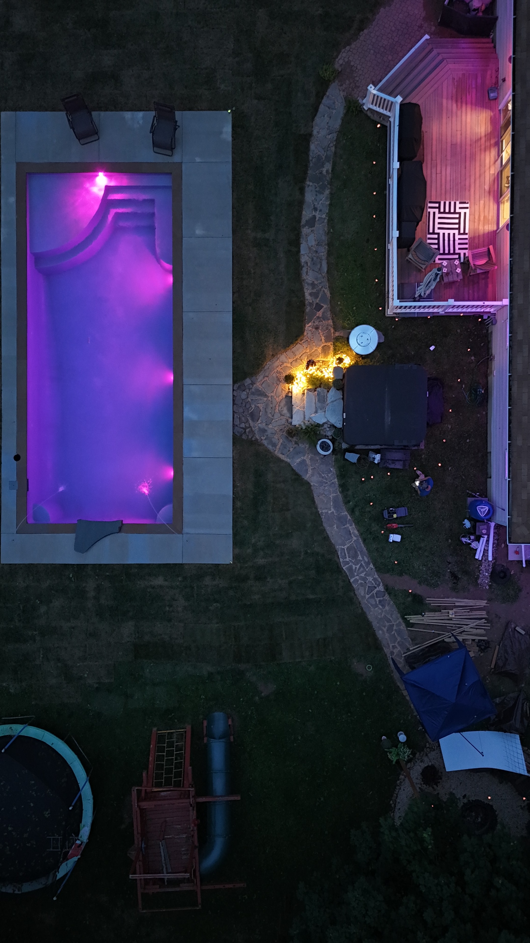 LandPro aerial night shot of pool glowing purple with stone path