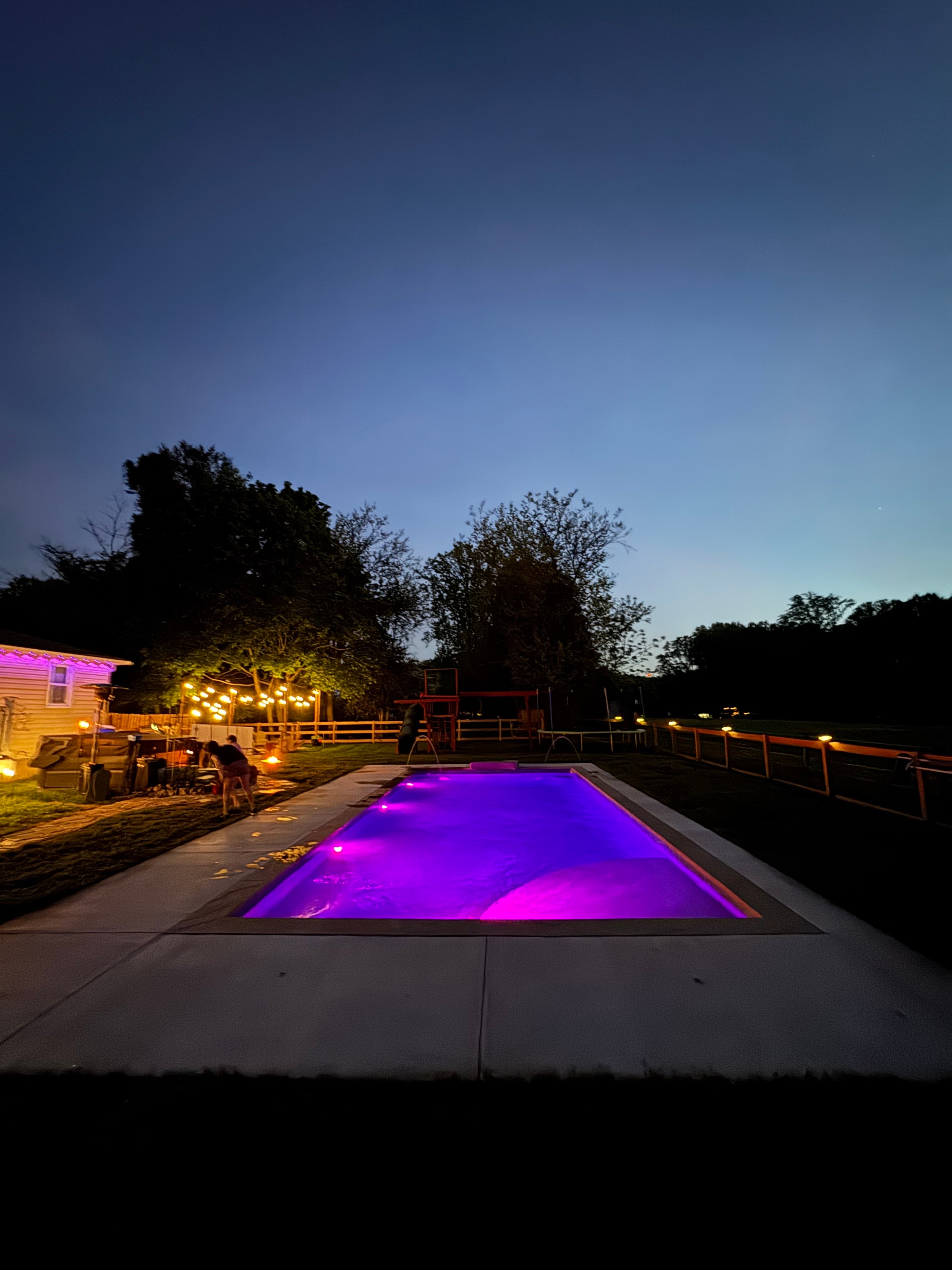 LandPro pool glowing purple at dusk with string lights