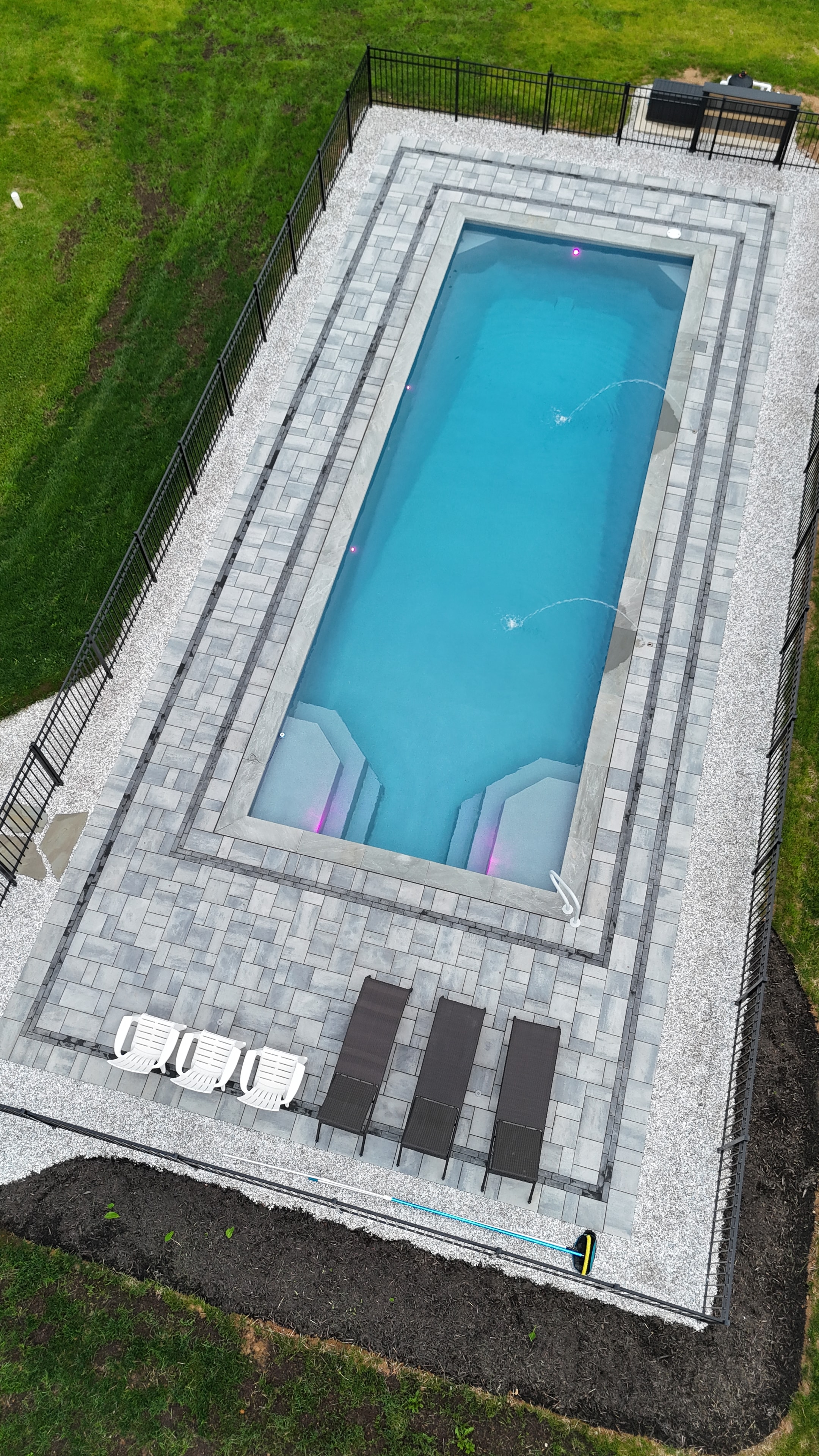LandPro aerial daytime shot of pool with paver surround, lounge chairs, and fountain jets