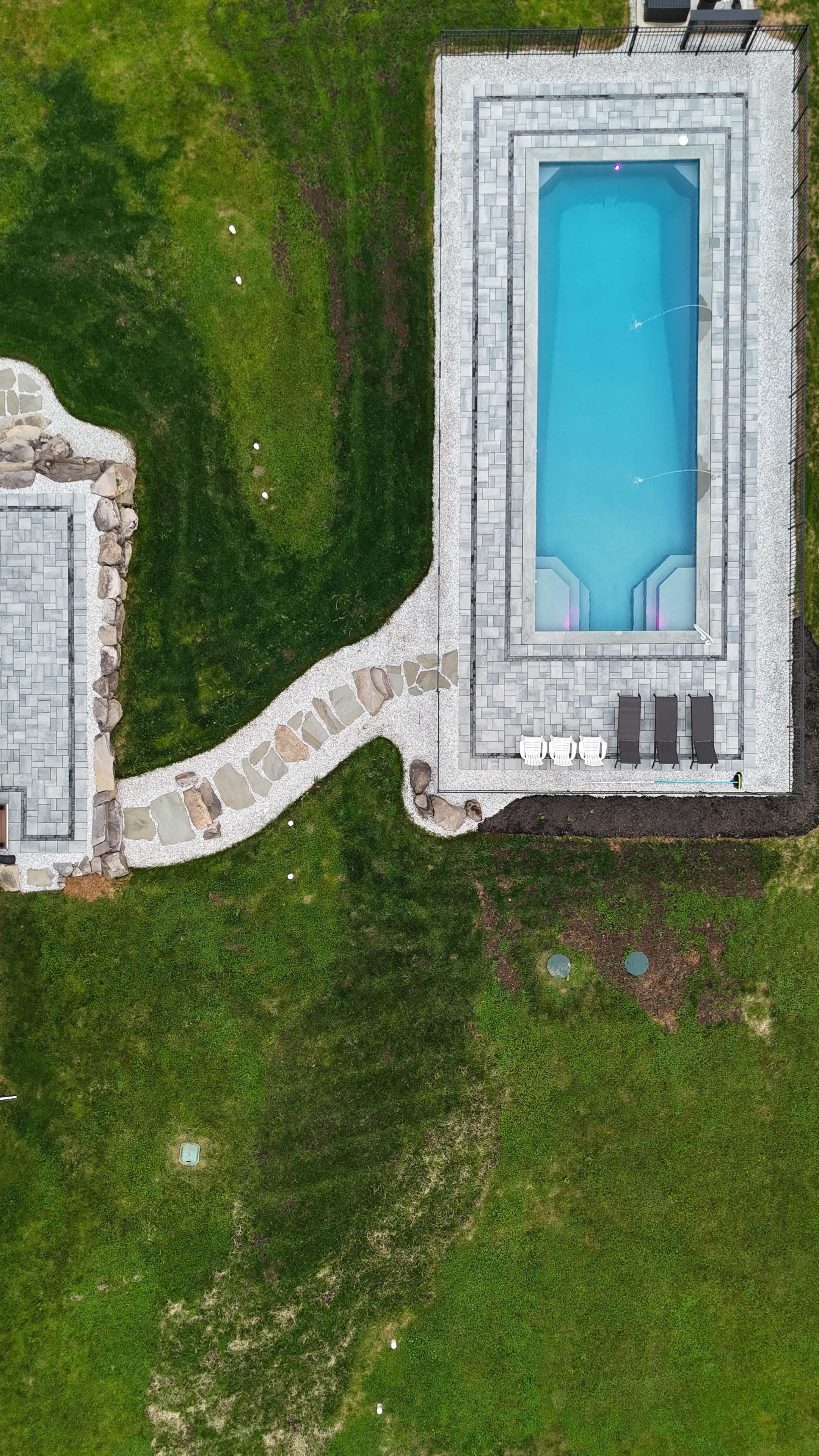 LandPro aerial daytime shot of pool with paver surround, flagstone path, and boulder sitting wall