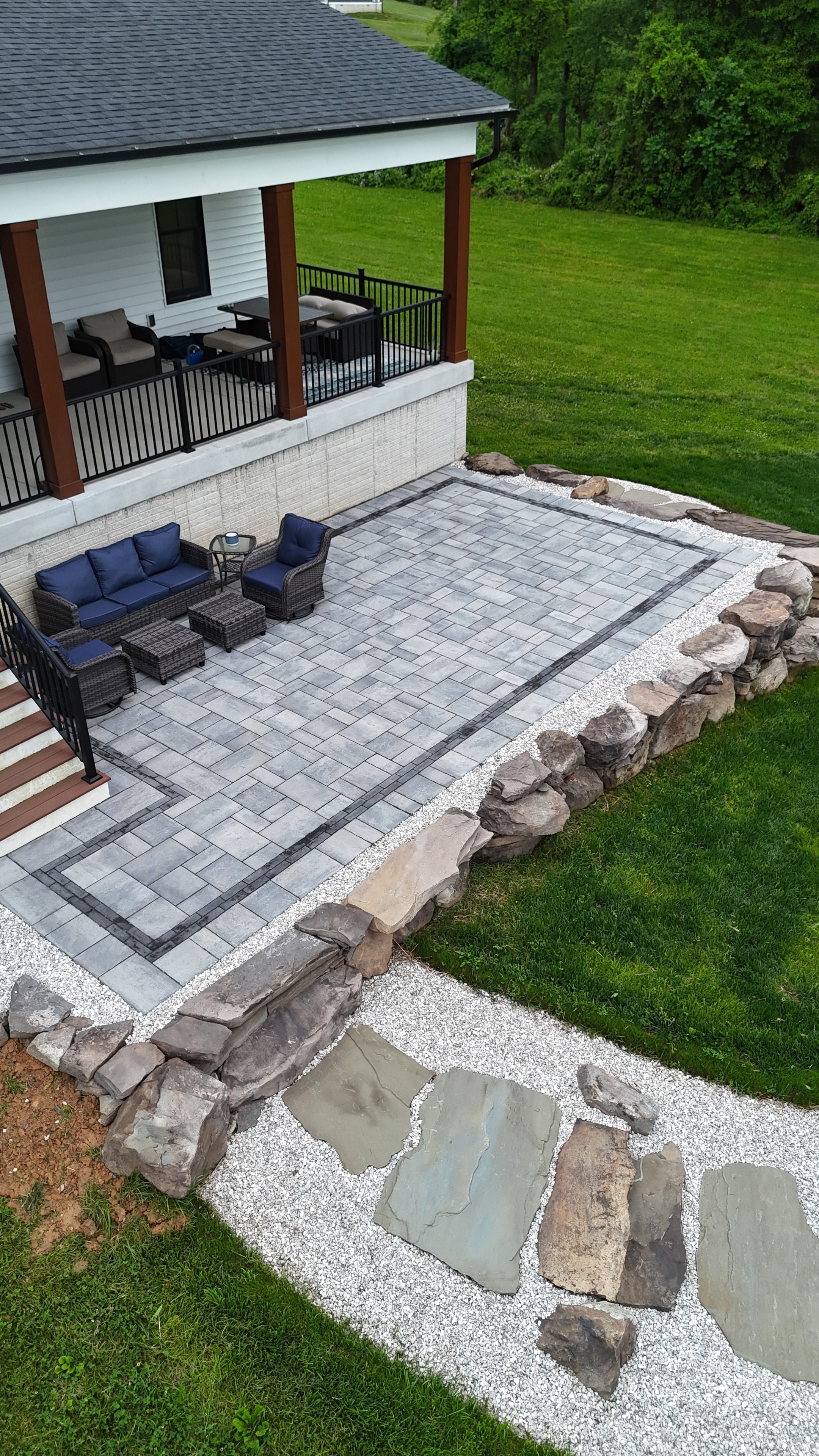 Country Oasis — aerial view of paver patio with outdoor furniture and boulder border