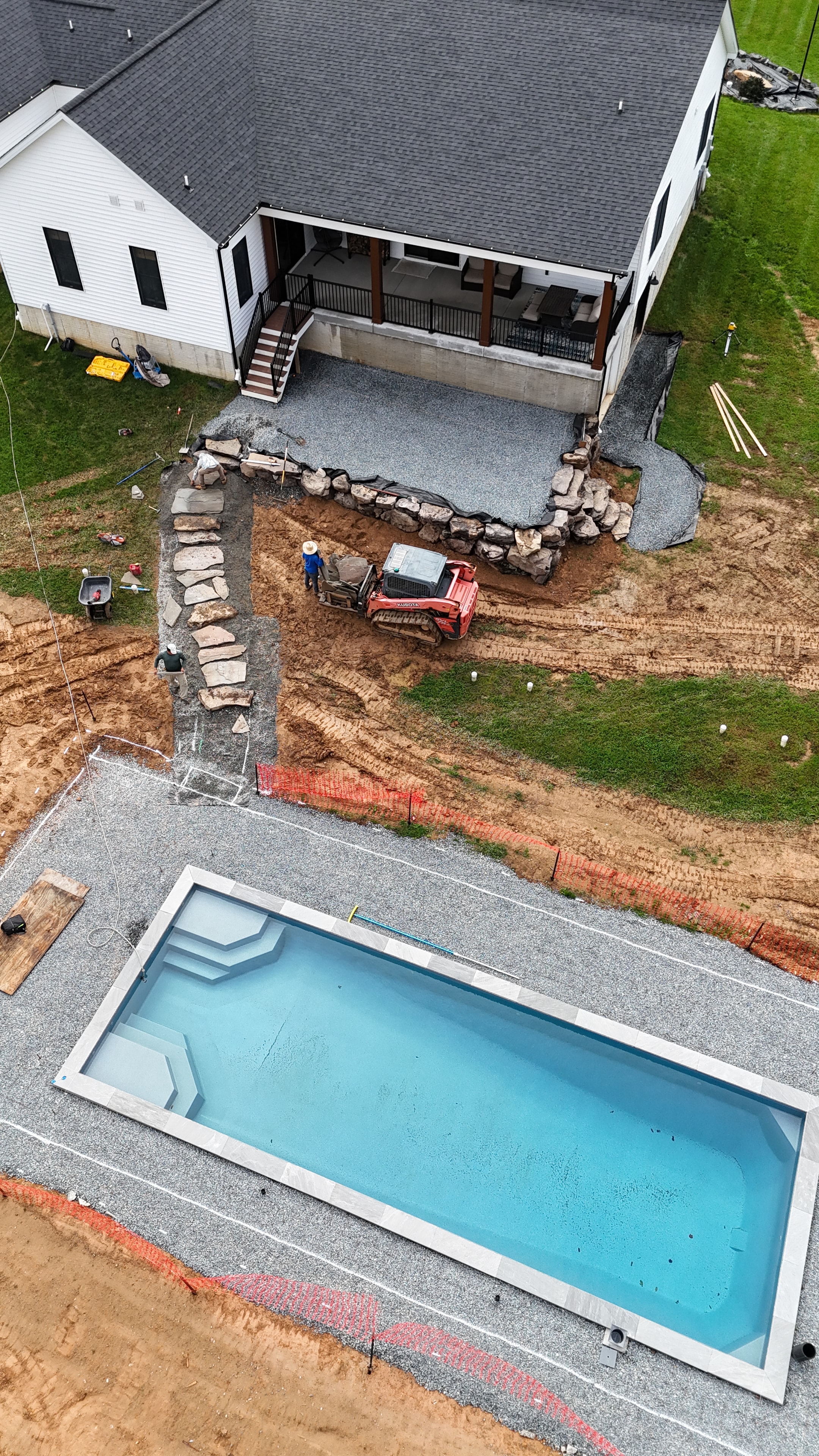Under construction — aerial view of pool shell installed with boulder border work in progress