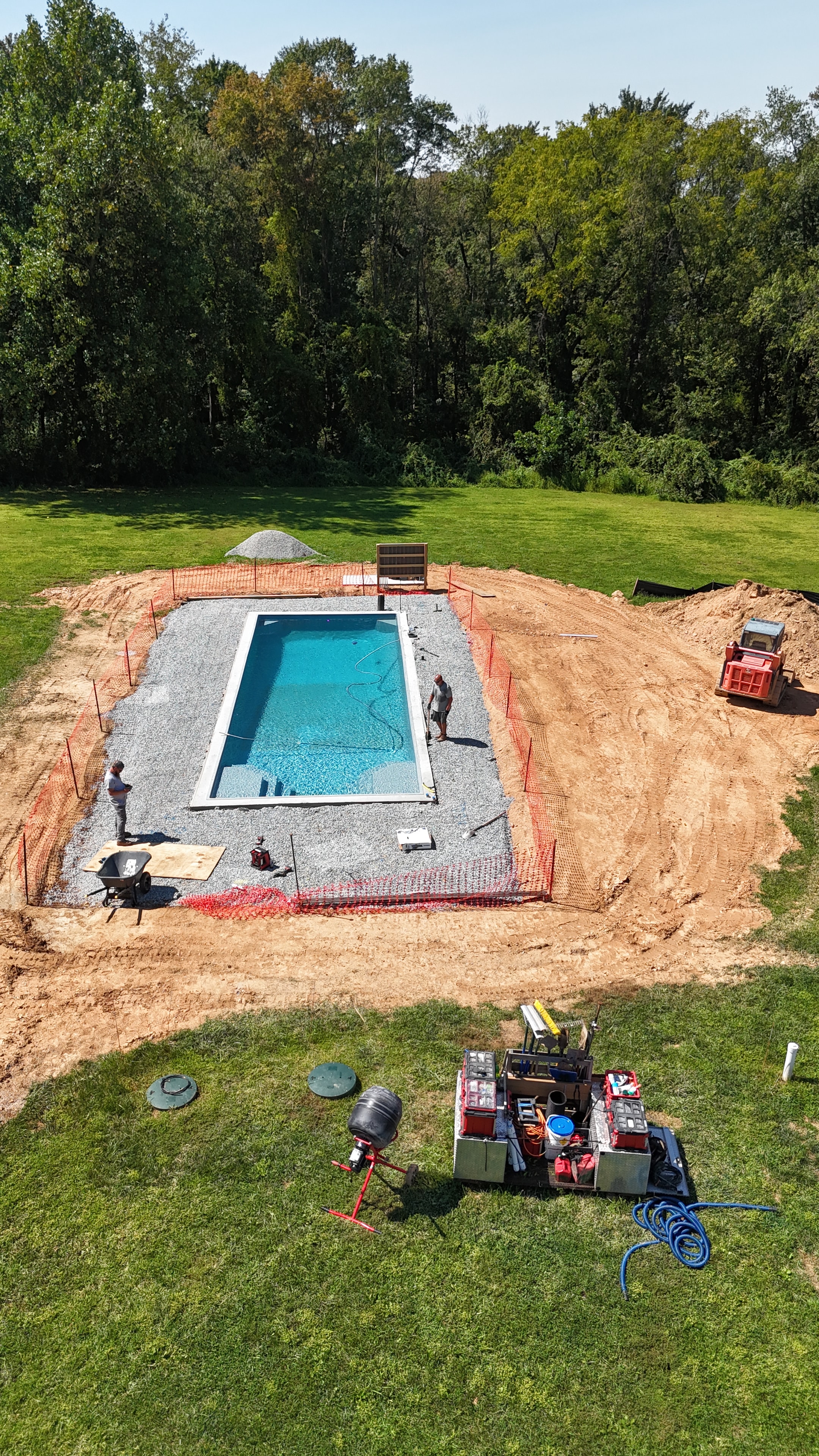 Under construction — aerial view of pool shell with gravel surround and equipment
