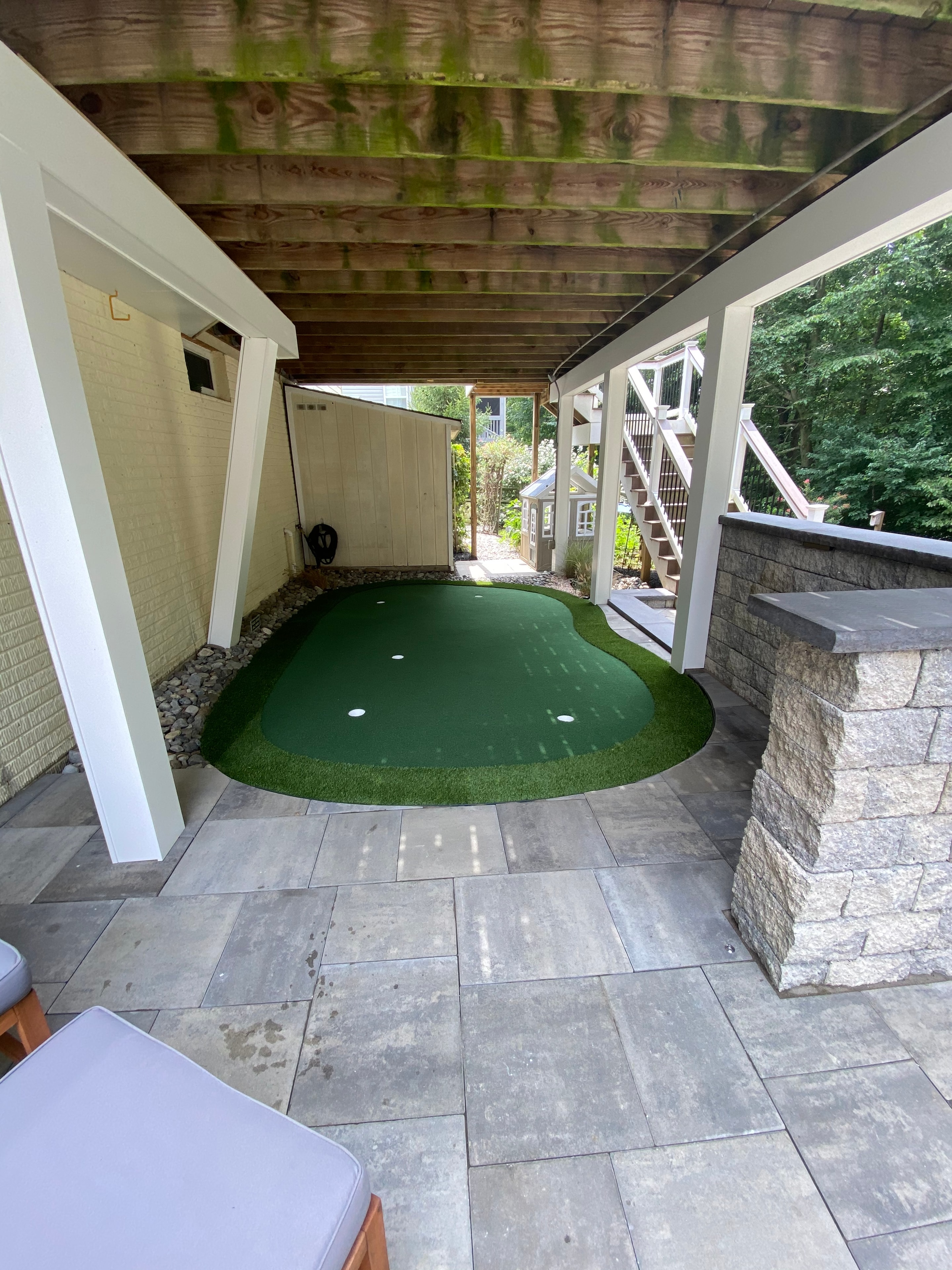 Golfing Paradise — overhead view of putting green with paver patio, pergola, and granite sitting wall
