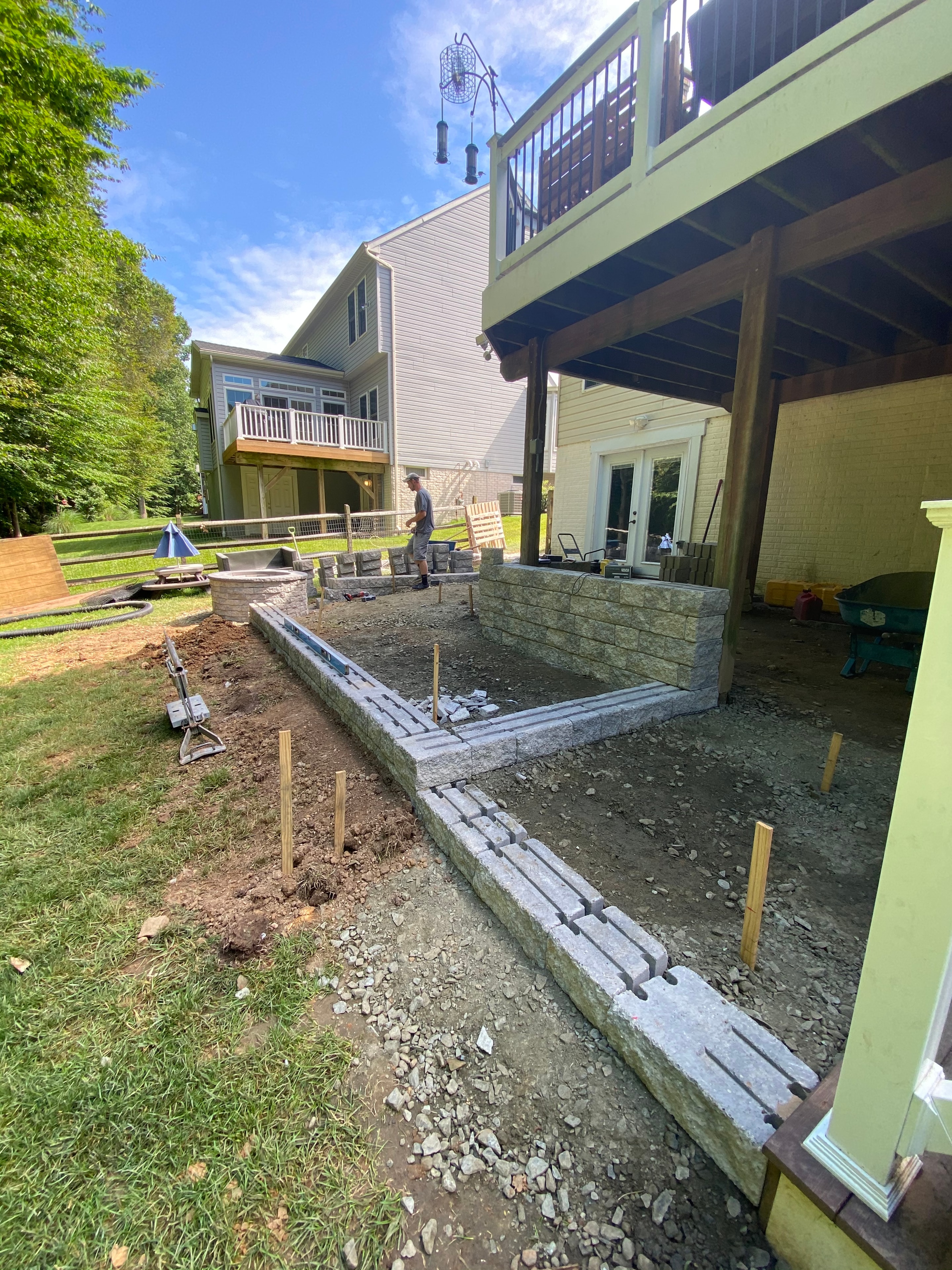 Under construction — granite sitting wall taking shape with crew working on site under blue sky
