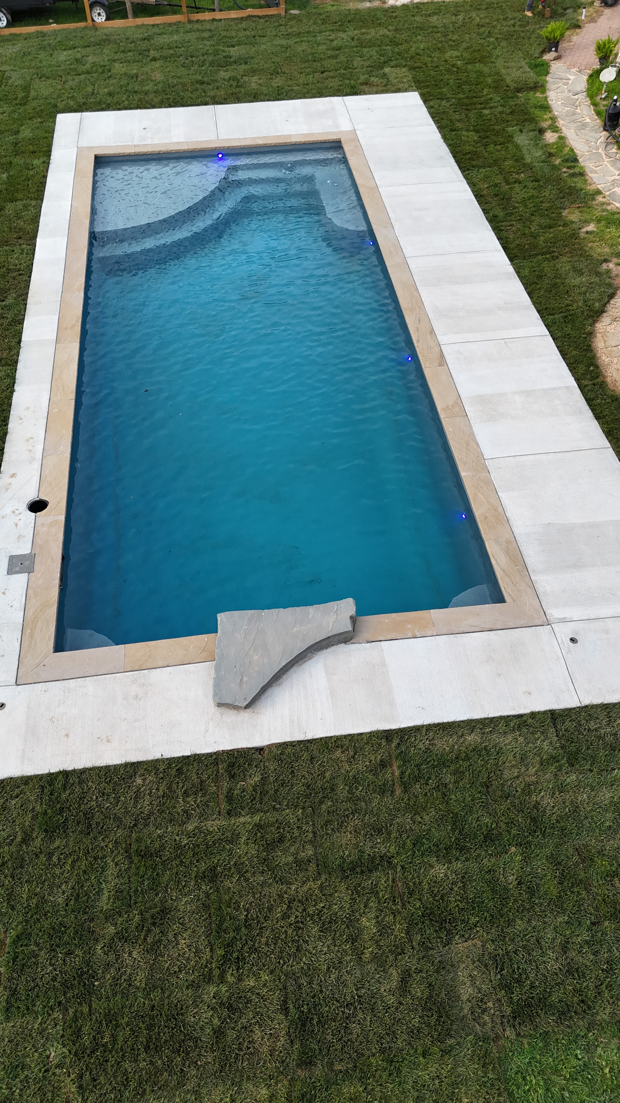 Light Up the Night — aerial daytime close-up of pool with blue LED lights and boulder water feature