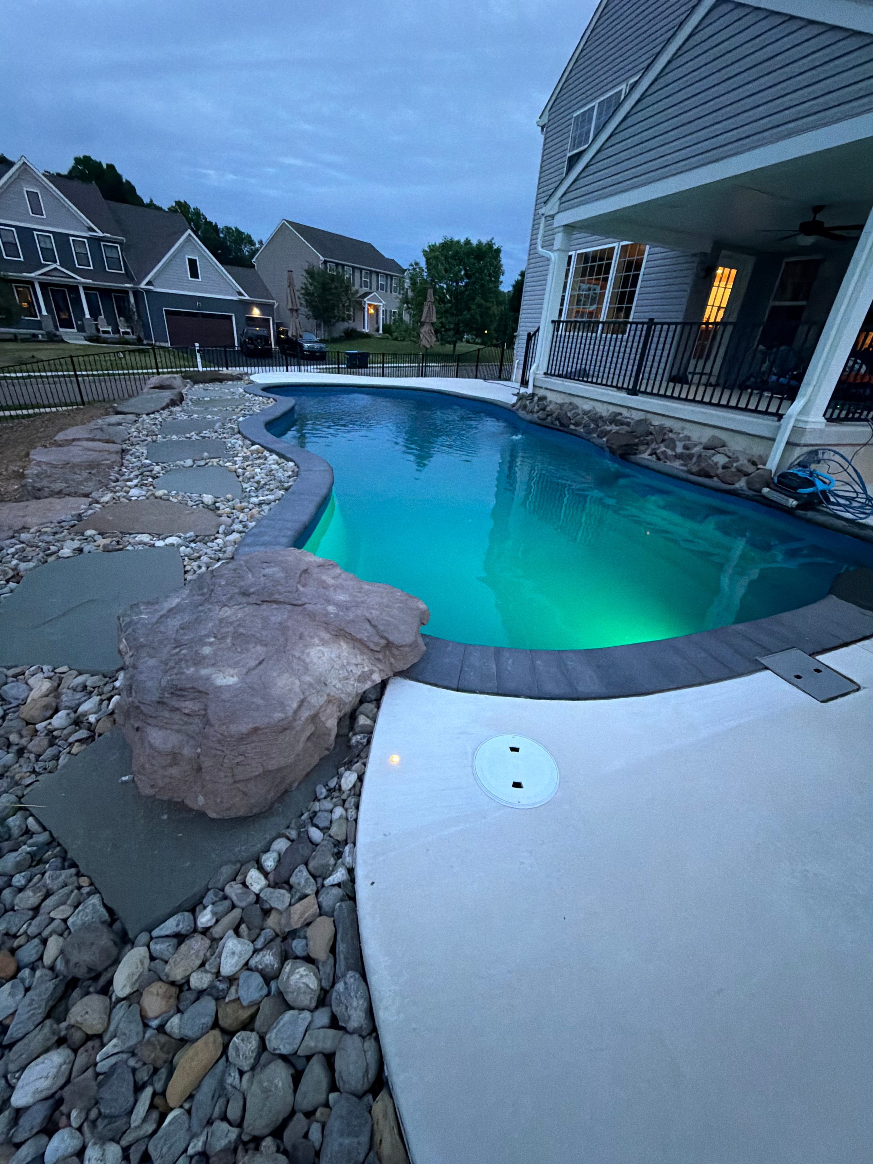 Tight Quarters — close-up of pool coping with large boulder accent and river rock border