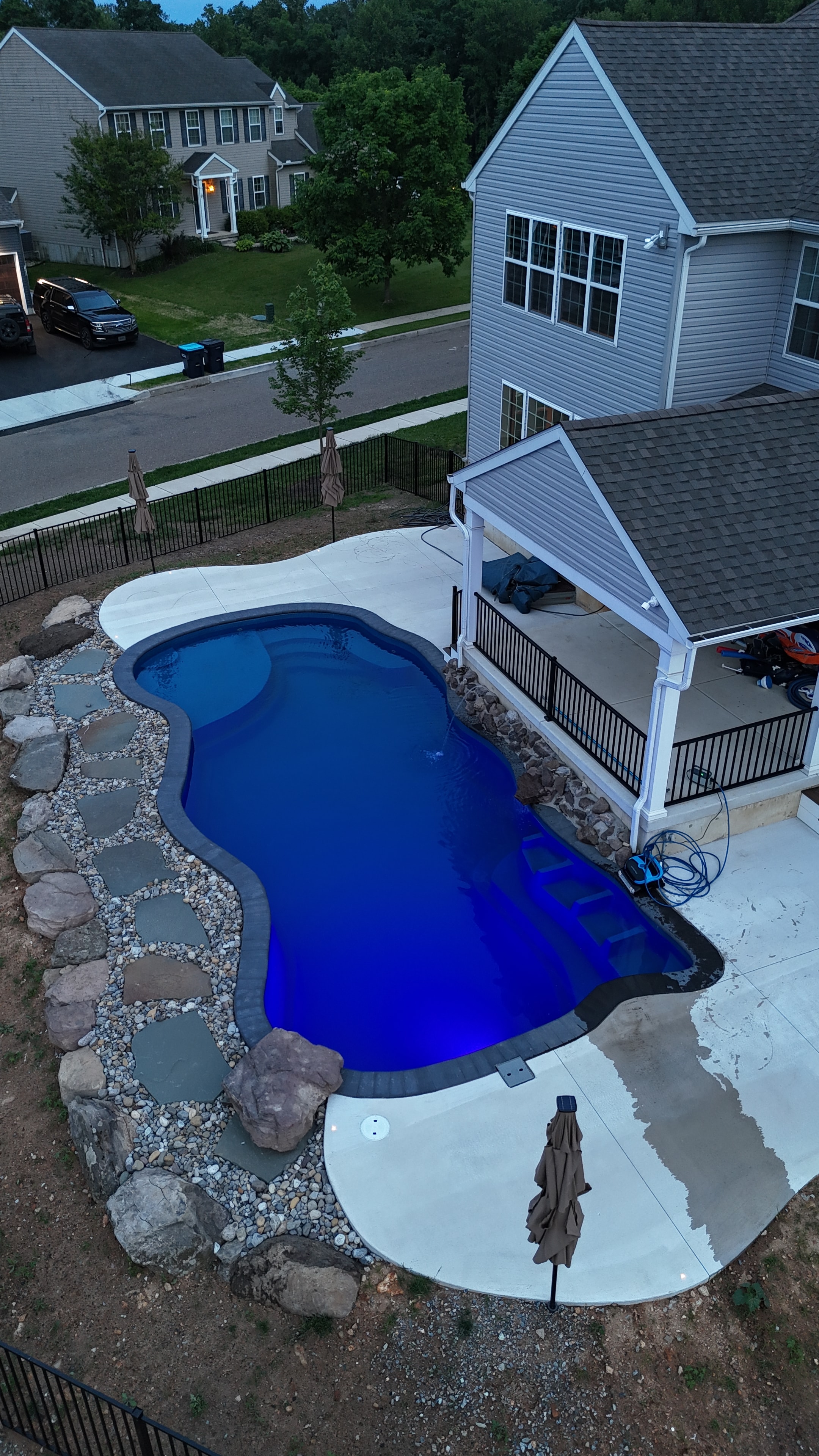 Tight Quarters — aerial nighttime shot of pool with blue LED light, concrete patio, and dark rock border