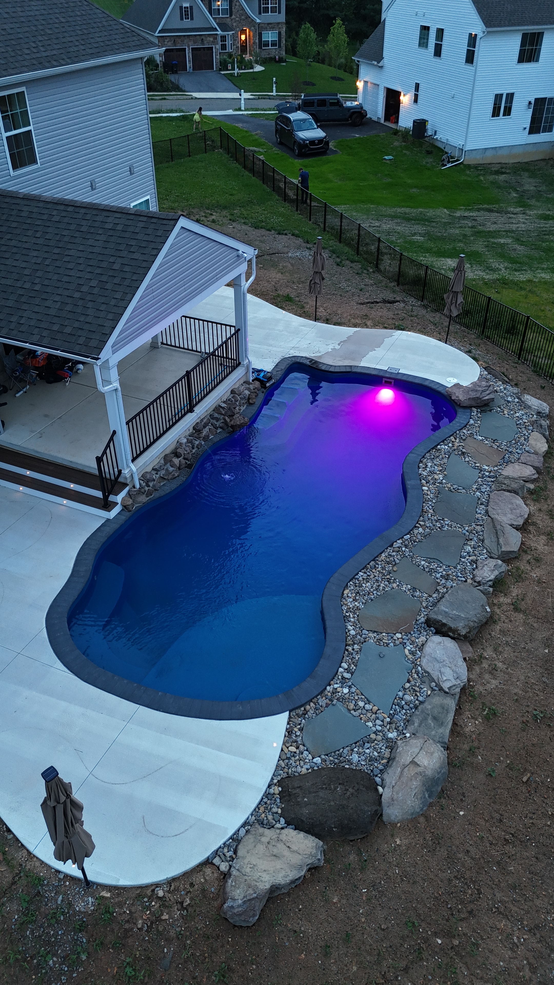 Tight Quarters — aerial nighttime overhead shot of pool with blue LED light, concrete surround, and pergola roof