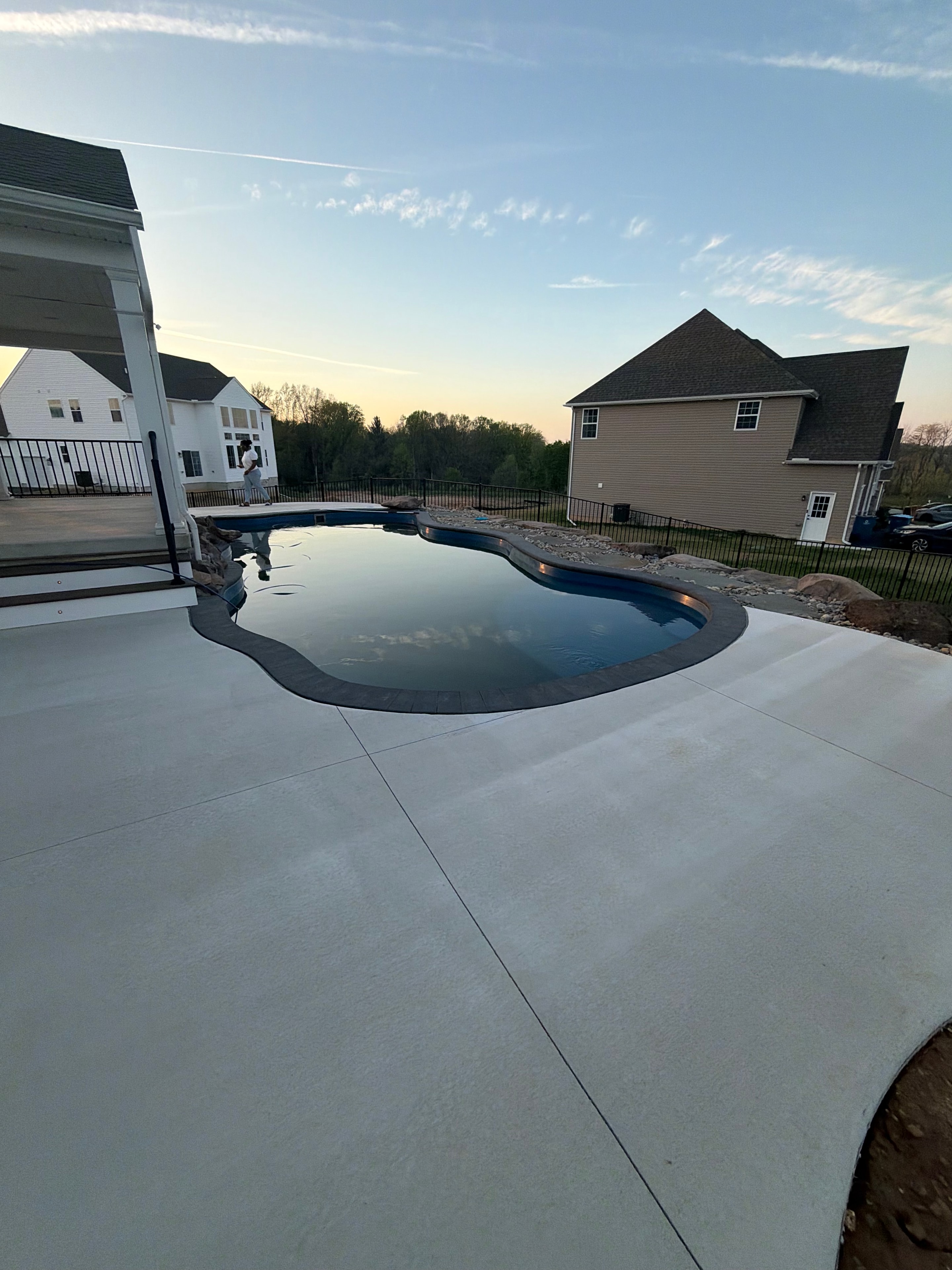 Tight Quarters — aerial dusk shot of pool with pink/purple LED light glowing, rock border, and concrete patio